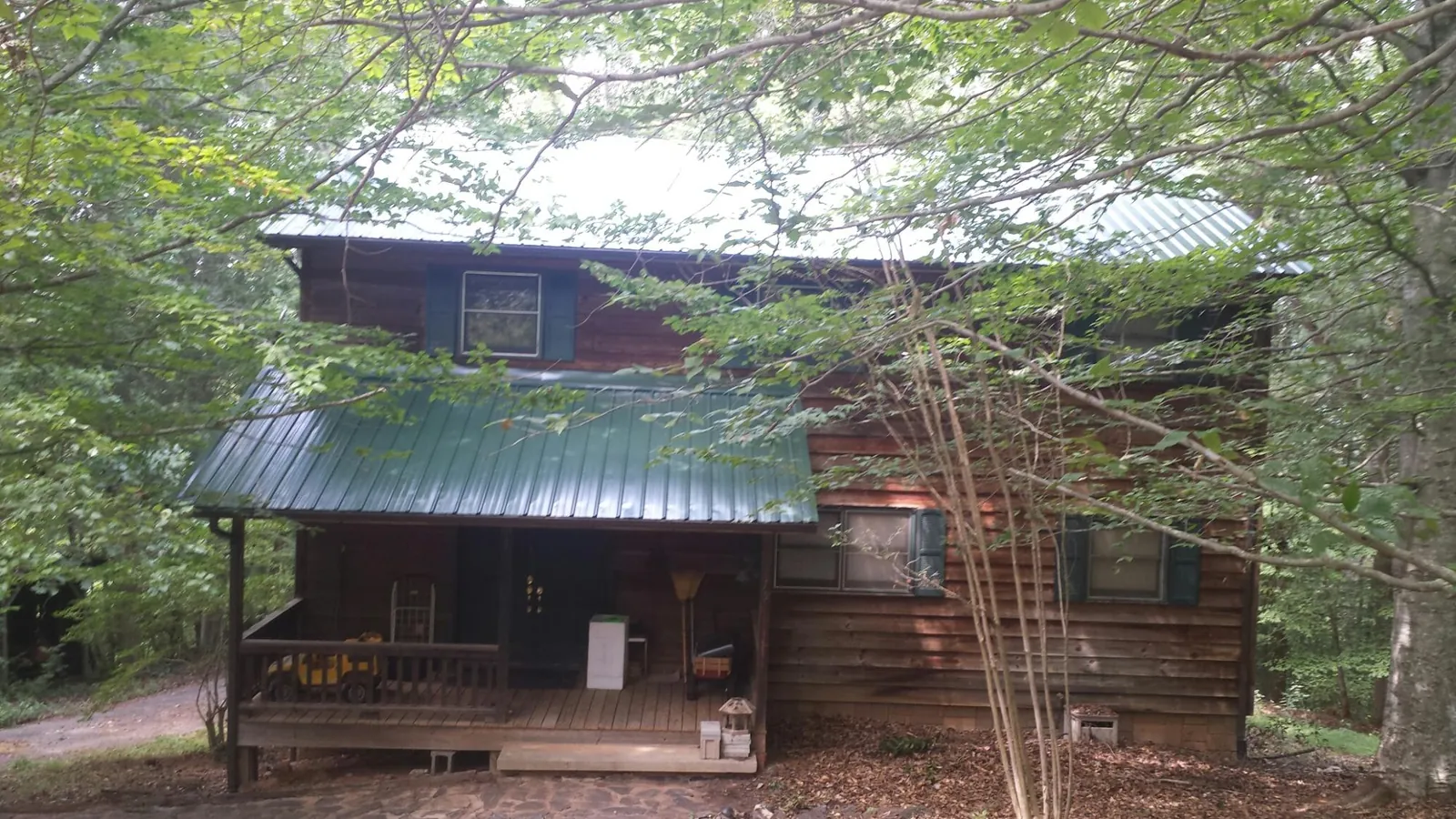 Green metal roof and covered porch on a log cabin in Montgomery